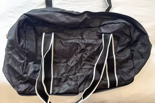 An empty Paravel Fold-Up Bag on a white bed