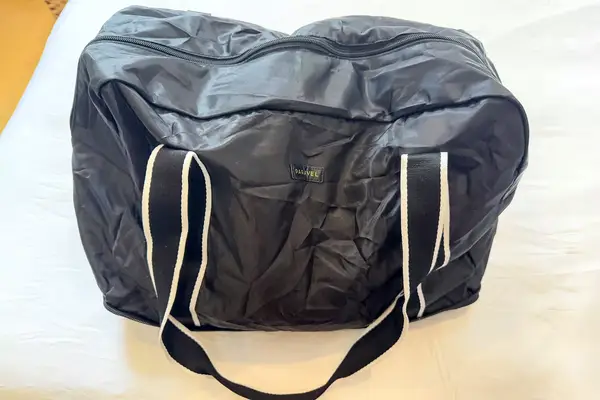 A closed Paravel Fold-Up Bag on a white bed
