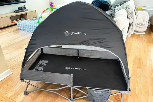 The Baby Delight Go With Me Bungalow Deluxe Portable Travel Cot open on a wooden floor