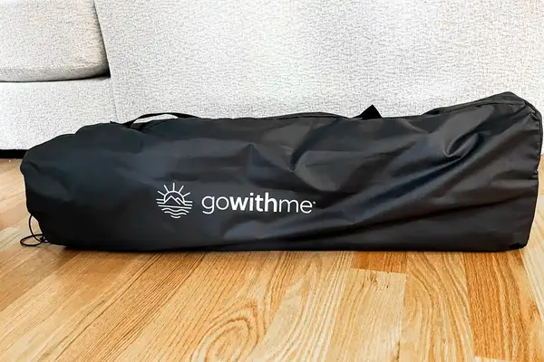 The Baby Delight Go With Me Bungalow Deluxe Portable Travel Cot folded up inside a branded storage bag