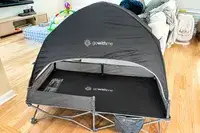 The Baby Delight Go With Me Bungalow Deluxe Portable Travel Cot open on a wooden floor