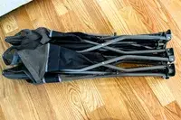 The Baby Delight Go With Me Bungalow Deluxe Portable Travel Cot folded up on a wooden floor