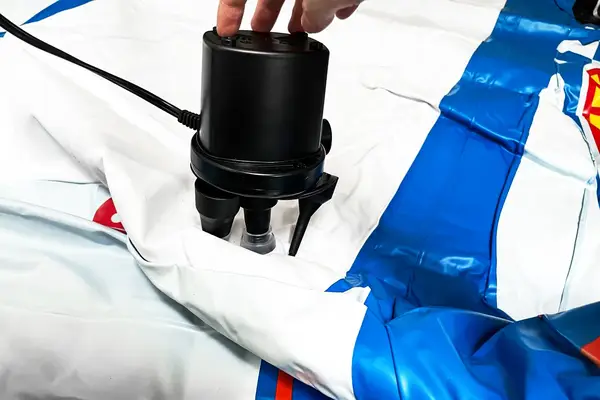 A person inflates the Funboy Kids Sleepover Air Mattress using an electric pump