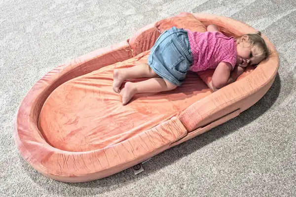 A child lies in the Sleepah Toddler Travel Bed & Chair