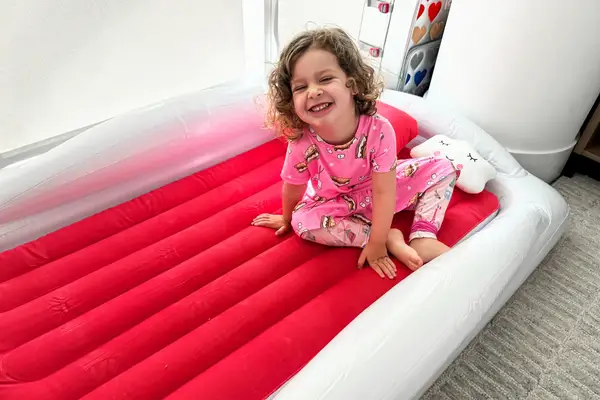 A child sits on the Sleepah Inflatable Toddler Travel Bed