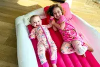 Two children lie in the Sleepah Inflatable Toddler Travel Bed