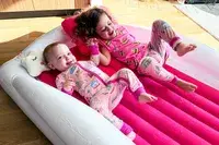Two children lie on the Sleepah Inflatable Toddler Travel Bed