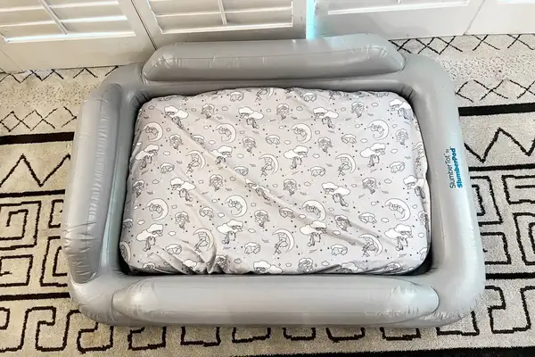 The fully inflated SlumberPod Slumber Tot Inflatable Toddler Bed on a colorful rug