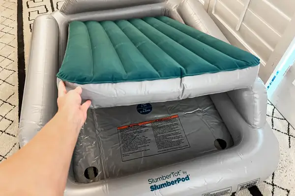 A person places an inflatable mattress into the SlumberPod Slumber Tot Inflatable Toddler Bed