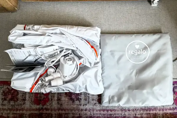 The Regalo Inflatable Toddler Bed folded up next to its storage bag