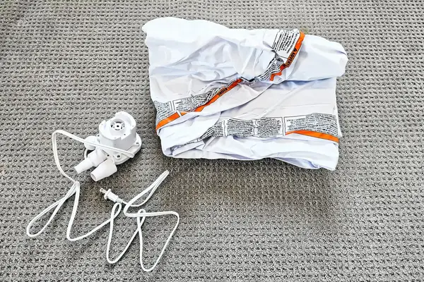 The Regalo Inflatable Toddler Bed rolled up next to an electric air pump