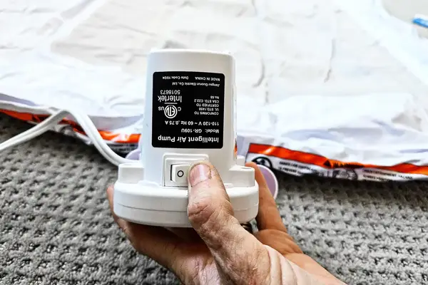 A person turns the electric pump on when inflating the Regalo Inflatable Toddler Bed