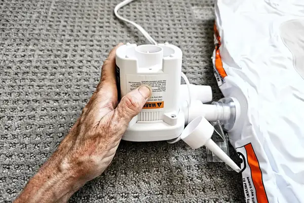 A person holds the air pump for the Regalo Inflatable Toddler Bed