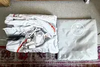 The Regalo Inflatable Toddler Bed folded up next to its storage bag