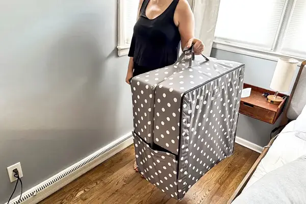 A person lifts the Milliard Portable Toddler Folding Floor Mat by the handles