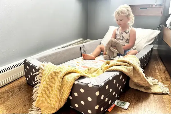 A child sits in the Milliard Portable Toddler Folding Floor Mat