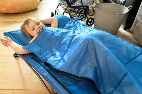 A child lies on the Regalo My Cot Deluxe Portable Toddler Bed