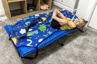 A child lays on the Regalo My Cot Deluxe Portable Toddler Bed