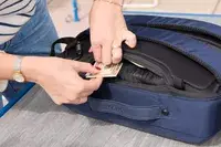A person places money into the XDDesign Bobby Bizz 3-in-1 Anti-Theft Backpack & Briefcase pocket