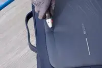 A person uses a box cutter to cut the XDDesign Bobby Bizz 3-in-1 Anti-Theft Backpack & Briefcase