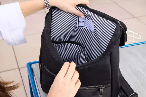 A person opens the Solo NY Stealth Hybrid Backpack