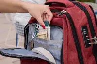 A person removes a cell phone and cash from the SHRRADOO Anti Theft Laptop Backpack pocket