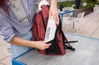 A person places a water bottle into the SHRRADOO Anti Theft Laptop Backpack