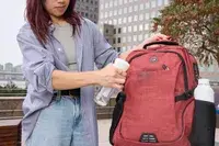 A person sprays the SHRRADOO Anti Theft Laptop Backpack with water
