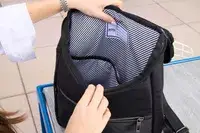 A person opens the Solo NY Stealth Hybrid Backpack