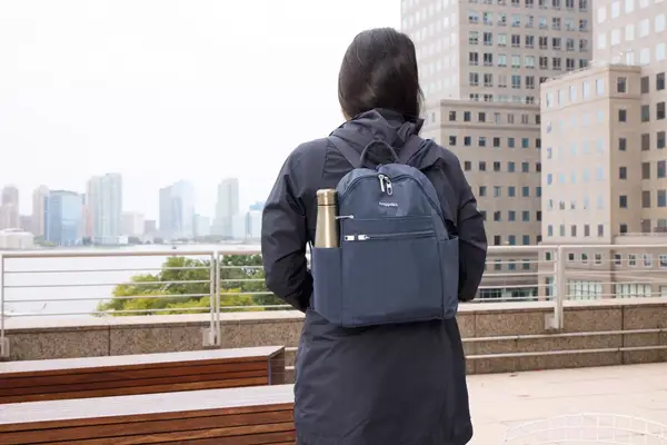 A person wears the Baggallini Securtex Anti-Theft Vacation Backpack while walking outside