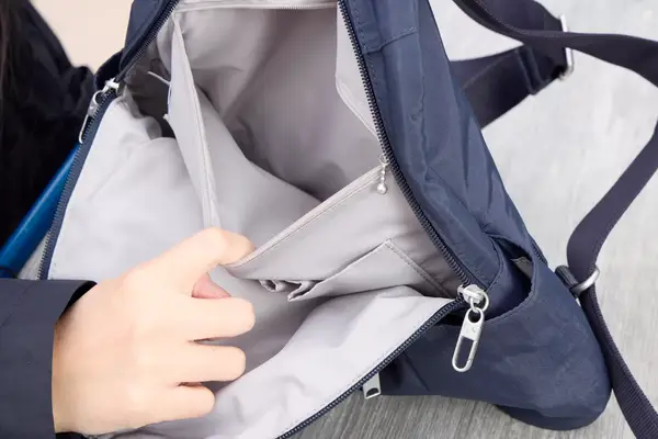 A person holds the Baggallini Securtex Anti-Theft Vacation Backpack pocket open