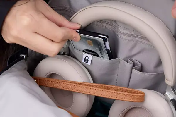 A person removes a credit card from the Baggallini Securtex Anti-Theft Vacation Backpack pocket
