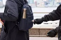 A person removes a wallet from the Baggallini Securtex Anti-Theft Vacation Backpack front pocket