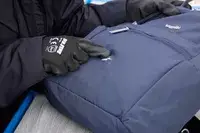 A person touches a rip in the fabric of the Baggallini Securtex Anti-Theft Vacation Backpack