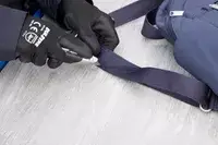 A person cuts the Baggallini Securtex Anti-Theft Vacation Backpack strap with a box cutter