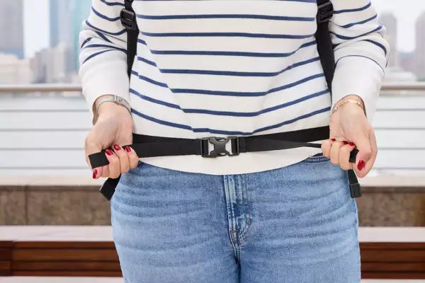 A person tightens the waist strap on the Pacsafe Venturesafe EXP45 Anti-Theft Carry-On Travel Pack