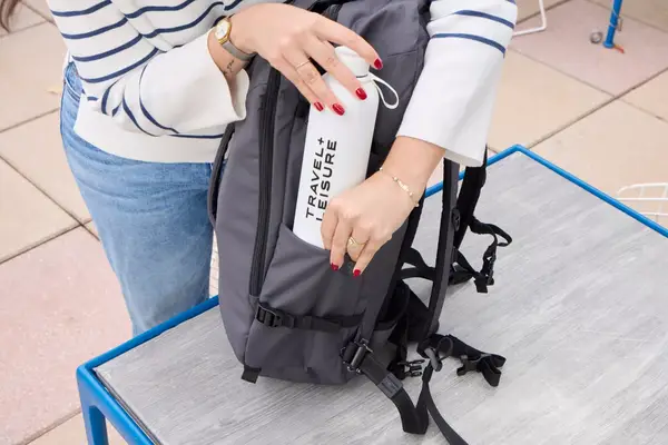 A person places a water bottle into the Pacsafe Venturesafe EXP45 Anti-Theft Carry-On Travel Pack