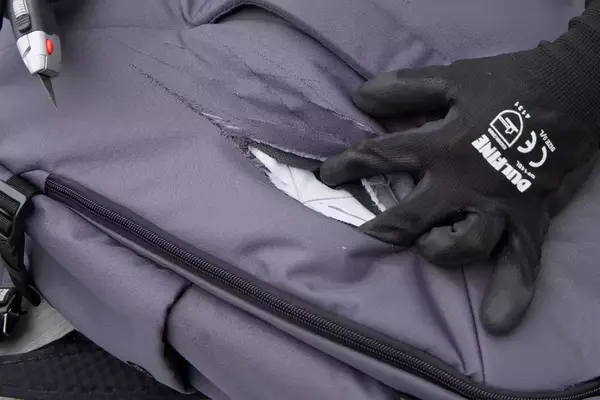 A person slices the Pacsafe Venturesafe EXP45 Anti-Theft Carry-On Travel Pack with a box cutter