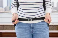 A person tightens the waist strap on the Pacsafe Venturesafe EXP45 Anti-Theft Carry-On Travel Pack