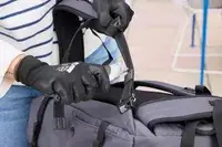 A person cuts the strap on the Pacsafe Venturesafe EXP45 Anti-Theft Carry-On Travel Pack with a box cutter