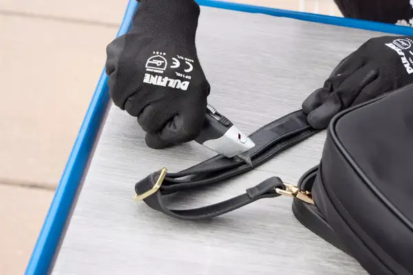 A person cuts the Arden Cove Carmel Convertible Backpack and Crossbody strap with a box cutter