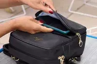 A person places a cell phone into the Arden Cove Carmel Convertible Backpack and Crossbody