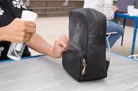 A person sprays water on the Arden Cove Carmel Convertible Backpack and Crossbody