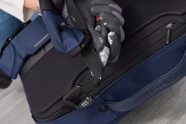 A person cuts the strap on the XDDesign Bobby Bizz 3-in-1 Anti-Theft Backpack & Briefcase with a box cutter