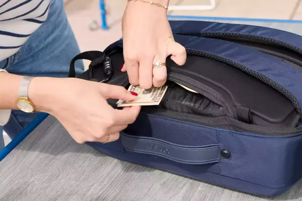 A person places money into the XDDesign Bobby Bizz 3-in-1 Anti-Theft Backpack & Briefcase pocket