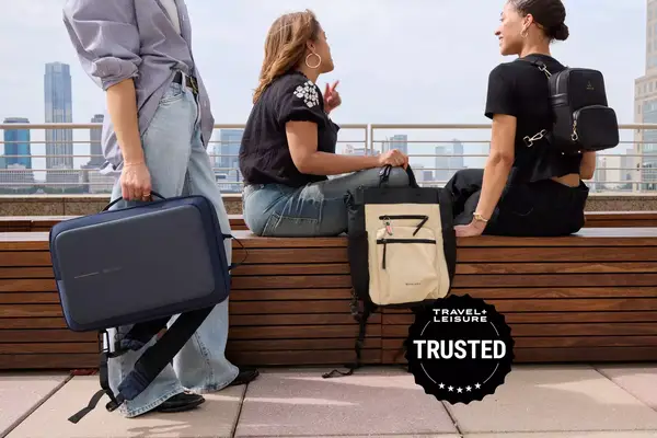 People sitting outside holding backpacks