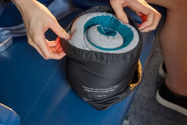 A person unpacking the Ostrich Pillow Go Neck Pillow on an airplane seat