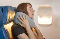 A person holding the Ostrich Pillow Go Neck Pillow on their neck