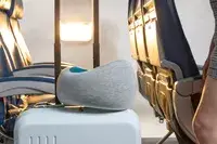 The Ostrich Pillow Go Neck Pillow resting on a suitcase