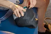 A person removing the Ostrich Pillow Go Neck Pillow from a travel pack